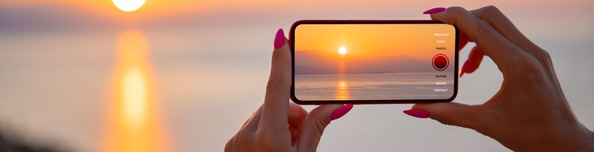 Mulher a tirar uma fotografia ao pôr do sol
