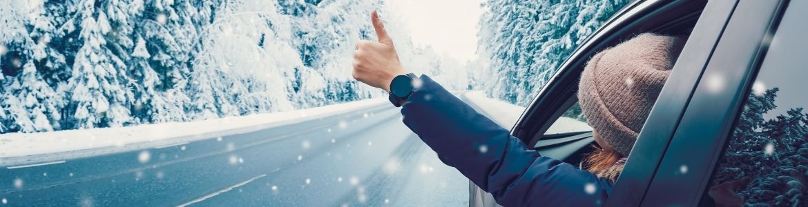 donna felice che gesticola in auto su una strada innevata